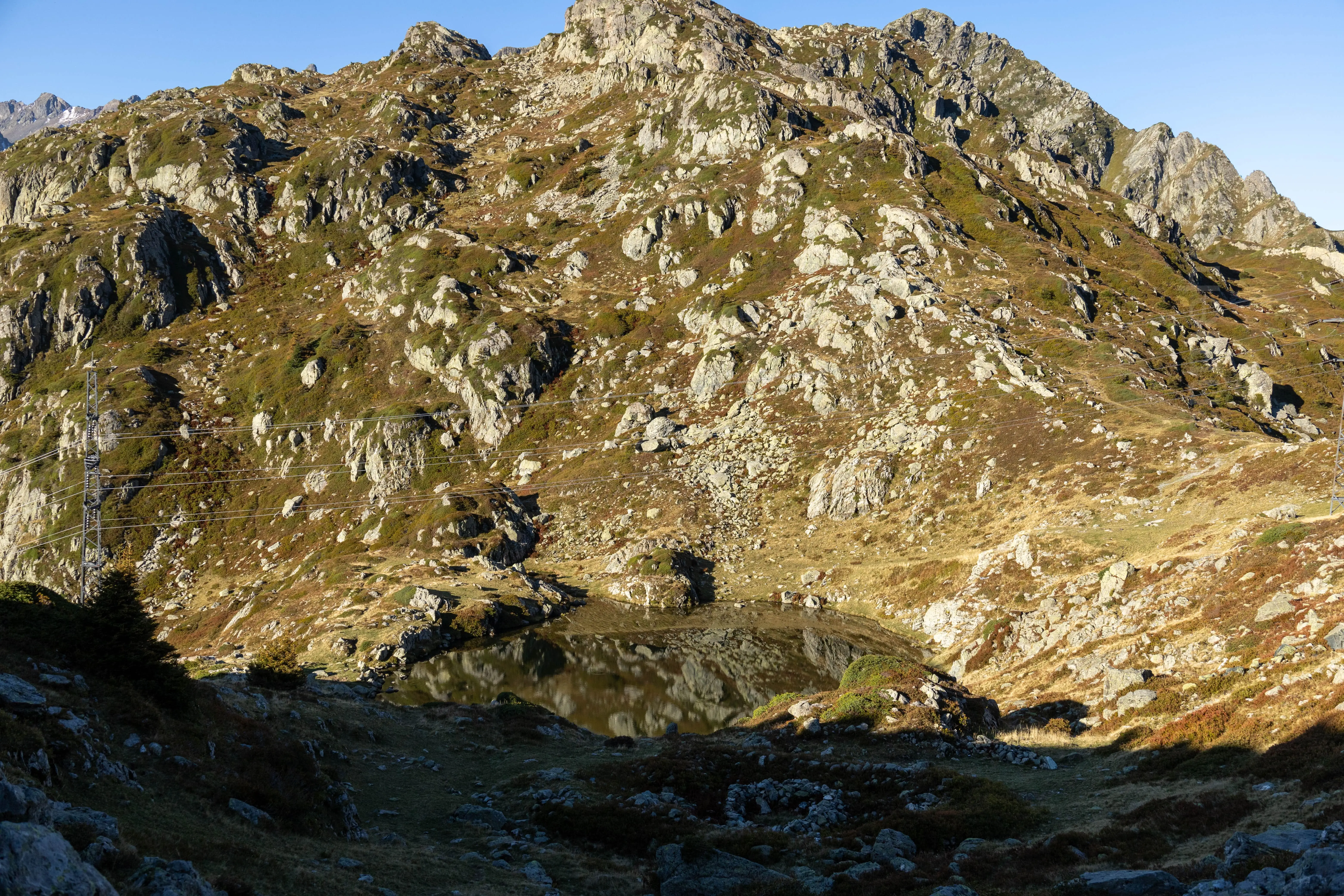 Le soleil levant au pas de la coche sur le tracés du GRP des 7 Laux, face au lac traversé par les lignes EDF de part et d'autre