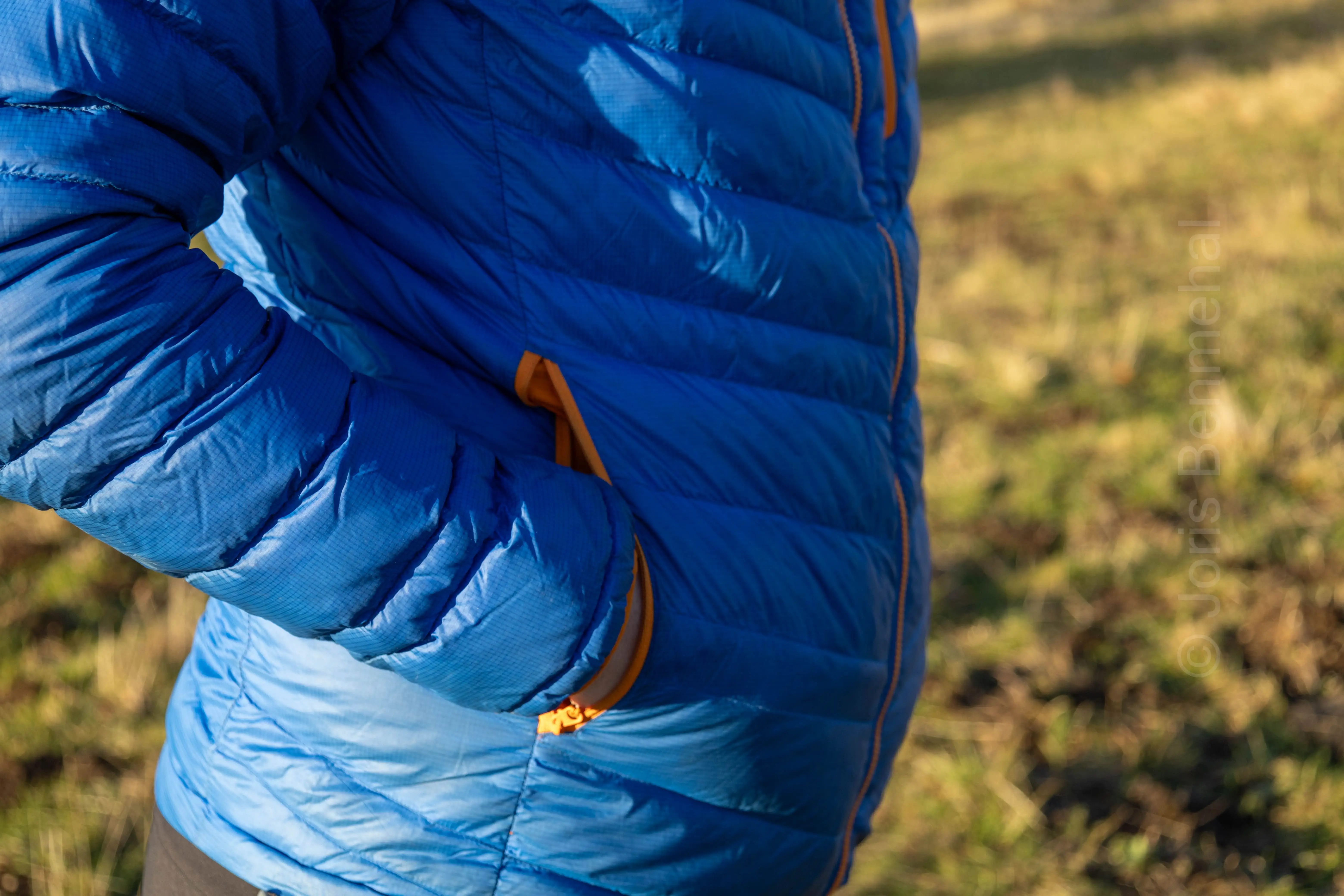 Main insérée dans la poche droite de la doudoune Simond en duvet bleu.