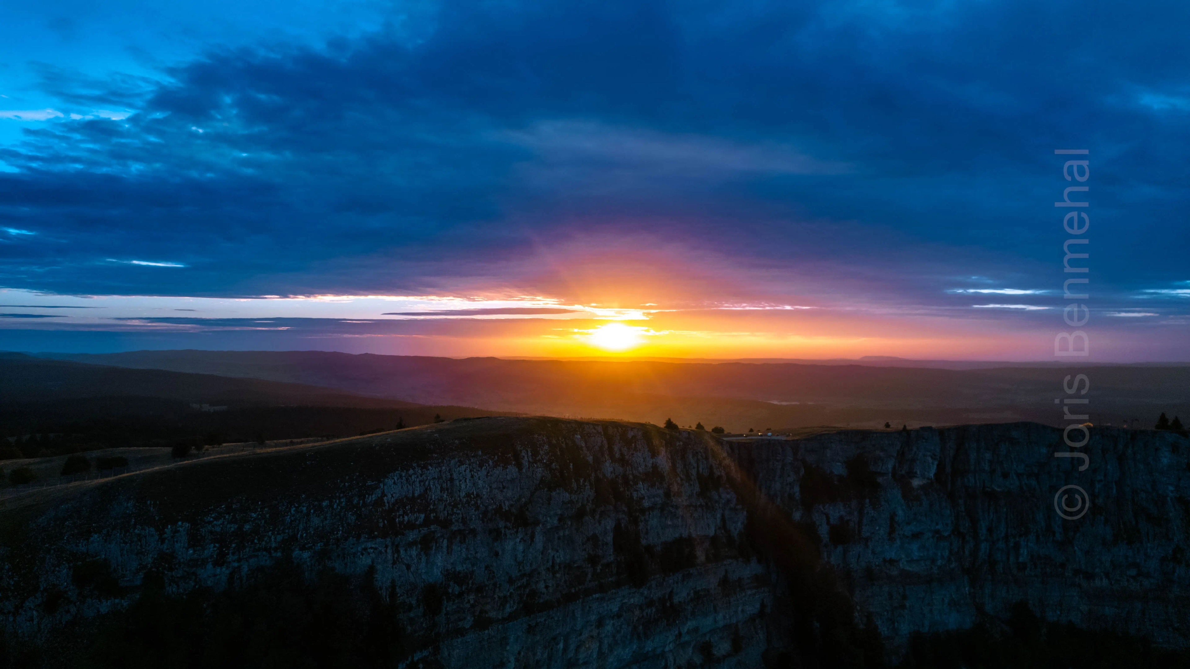 Vue aérienne au coucher du soleil révélant les crêtes montagneuses éclairées par une lumière douce.