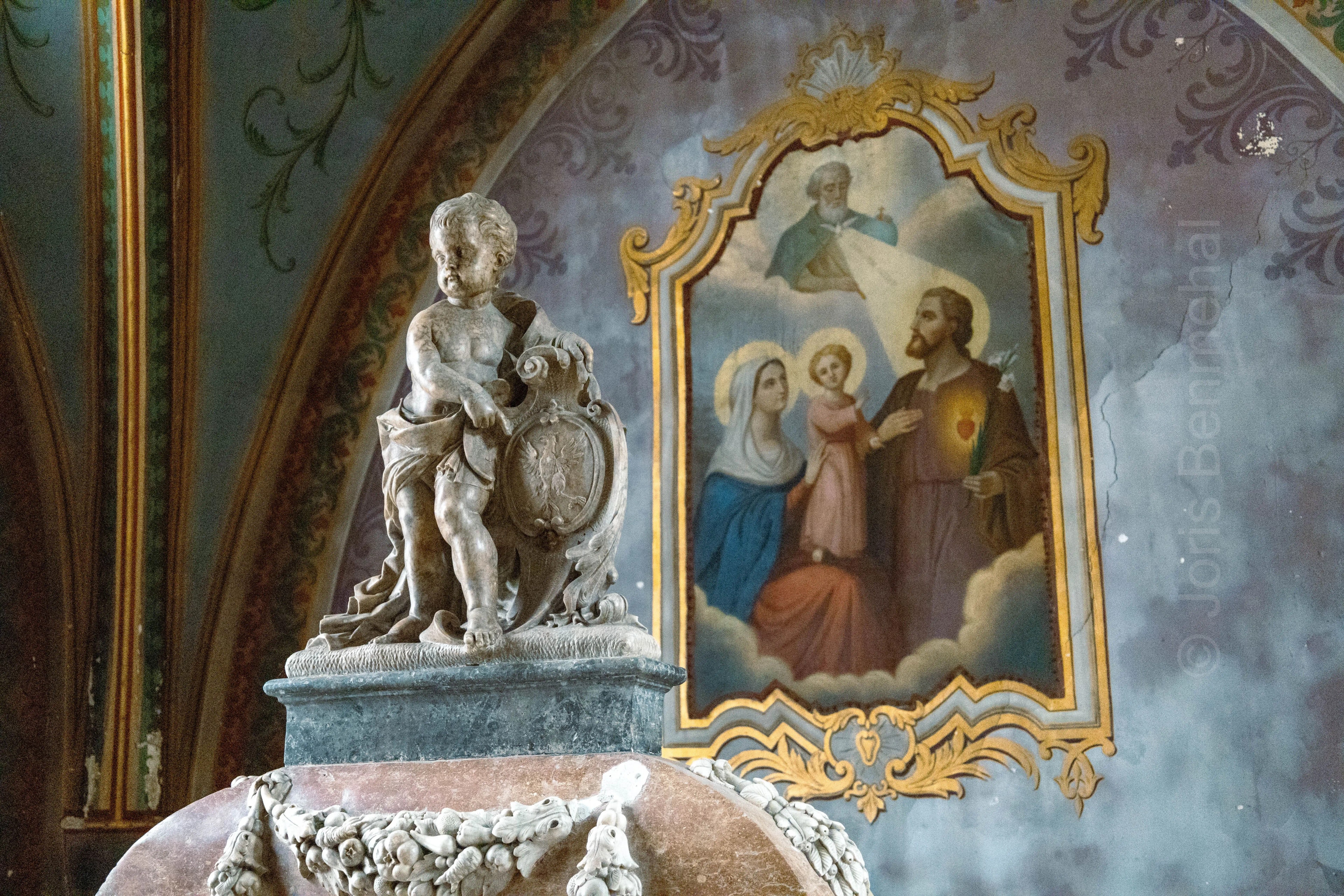 Statue d'un ange en marbre devant une fresque religieuse dans la chapelle de Consolation Maisonnette.