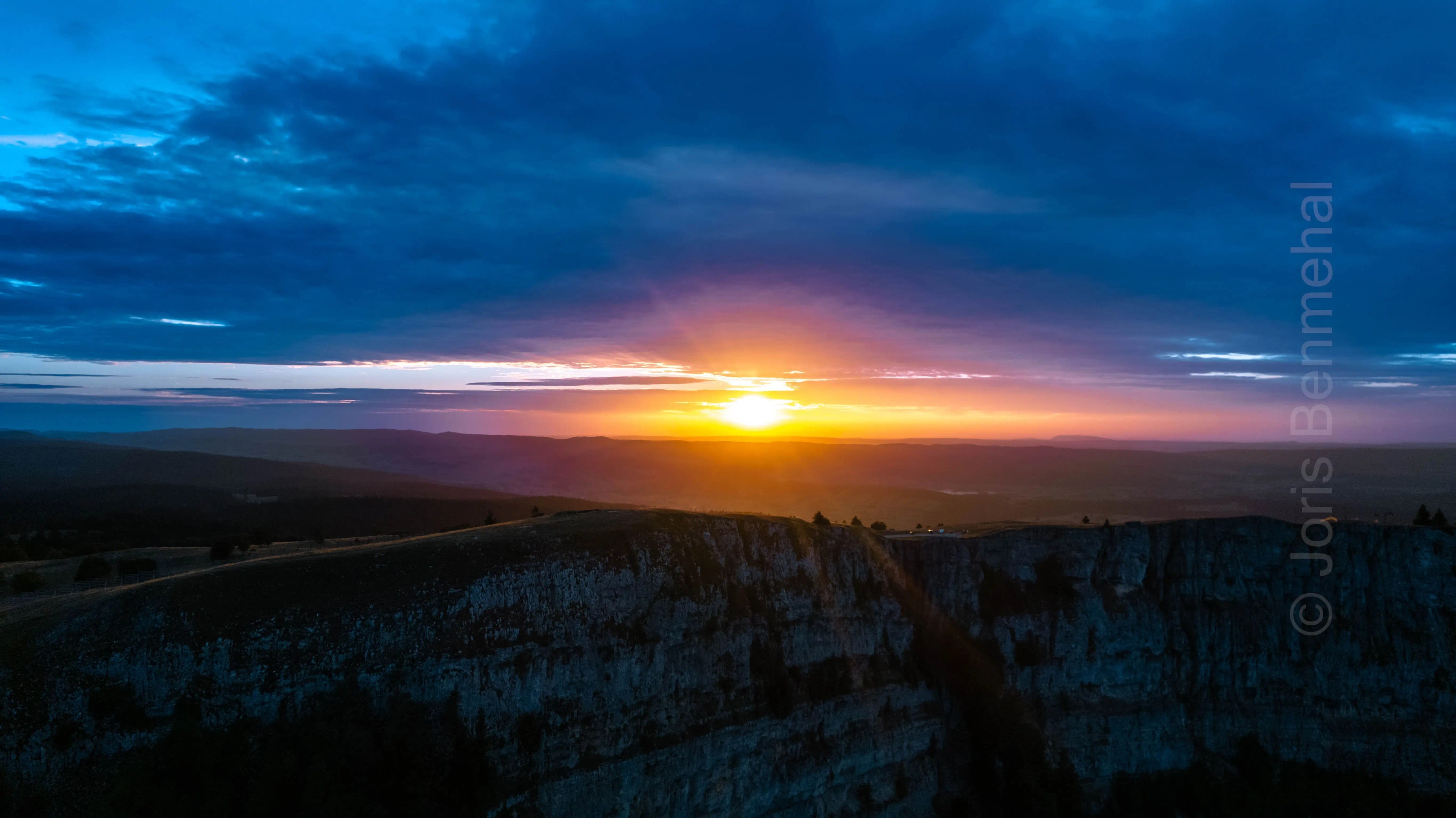 Vue aérienne au coucher du soleil révélant les crêtes montagneuses éclairées par une lumière douce.