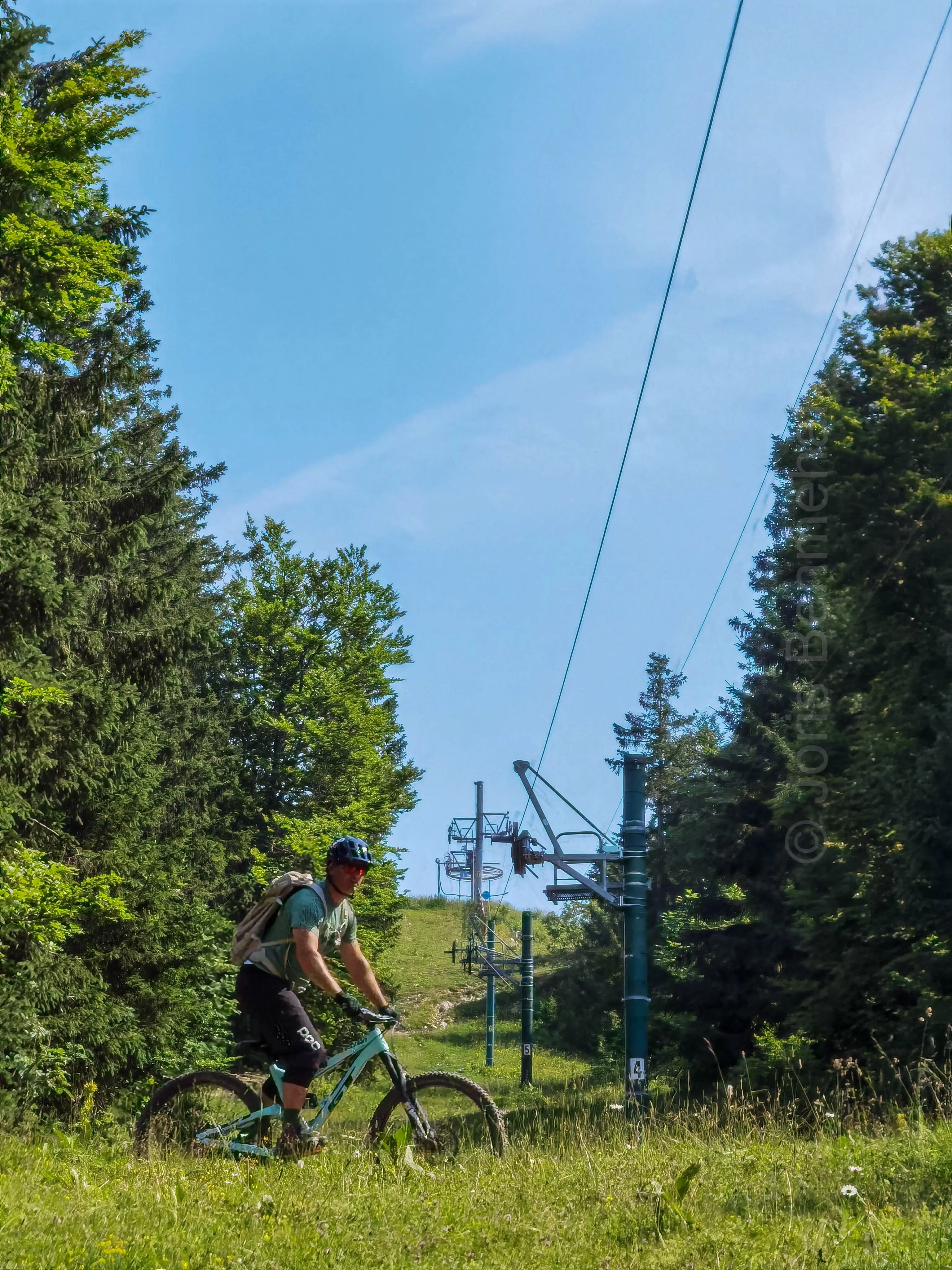 Cycliste descendant à grande vitesse une piste de DH sous le téléski de Super-Longeville.